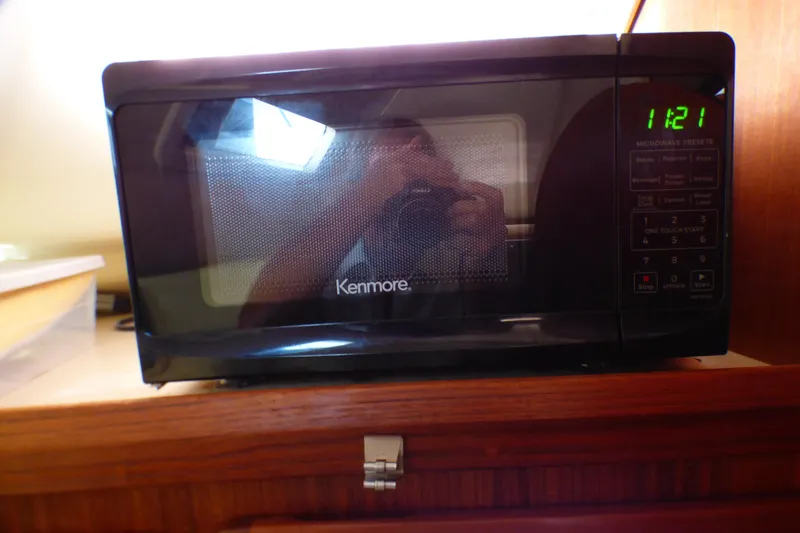 Slide: The Image of Kenmore microwave on wooden shelf, digital clock displaying 11:21, in a 1993 Hunter 40.5. - 30
