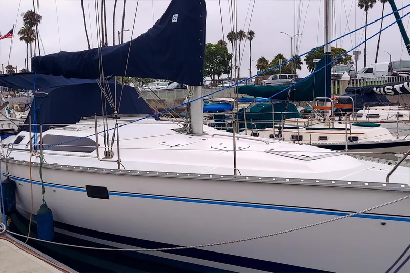 Slide: The Image of 1993 Hunter 40.5 sailboat docked in marina, surrounded by other boats and palm trees. - 8