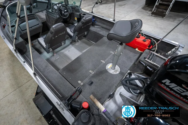 Slide: The Image of 2014 Lund 1650 Rebel XS boat interior with seating and controls, displayed in a showroom. - 15