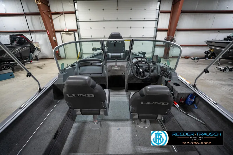 Slide: The Image of 2014 Lund 1650 Rebel XS boat interior with steering wheel and seating in a garage. - 16