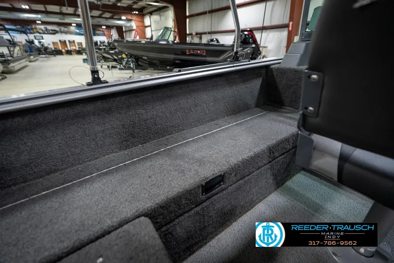 Slide: The Image of 2014 Lund 1650 Rebel XS boat interior in showroom, featuring carpeted seating and storage. - 24