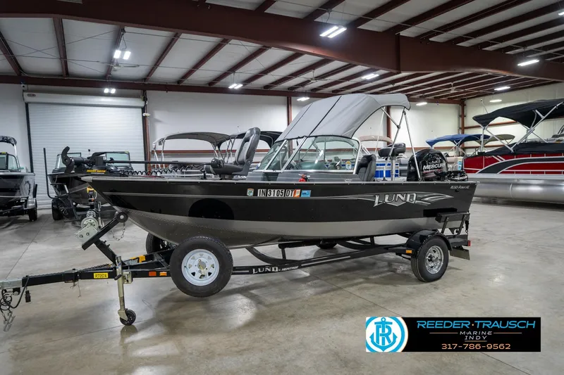 Slide: The Image of 2014 Lund 1650 Rebel XS boat in showroom, featuring trailer and canopy. - 4