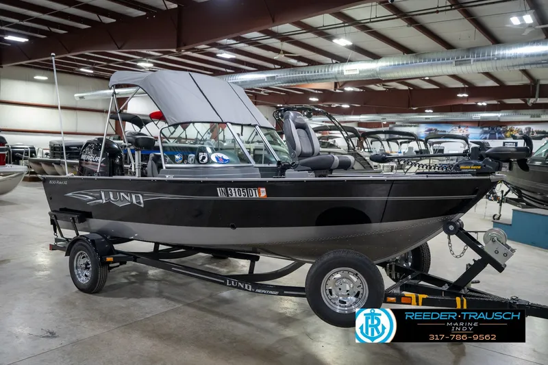 Slide: The Image of 2014 Lund 1650 Rebel XS boat in showroom, featuring canopy and trailer. - 6
