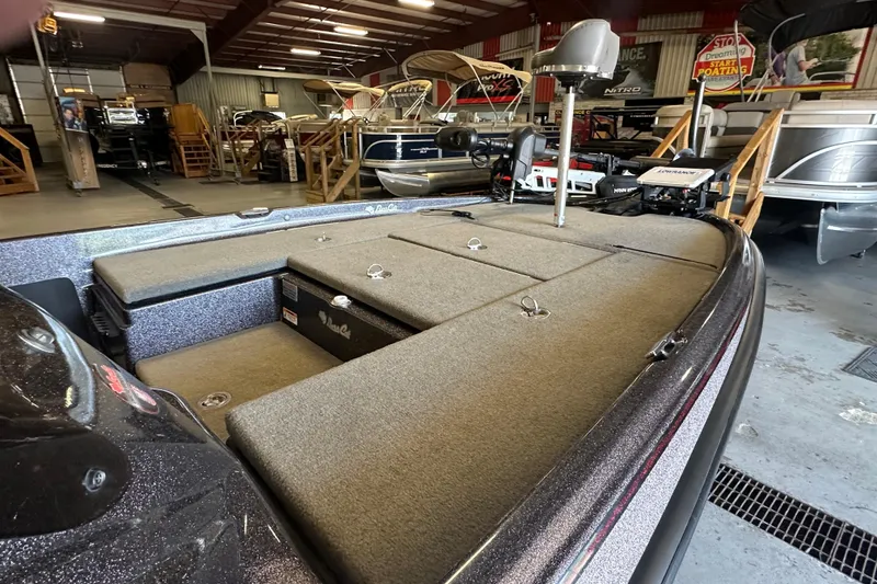 Slide: The Image of 2021 Bass Cat Pantera II boat interior in showroom, featuring carpeted deck and storage compartments. - 21