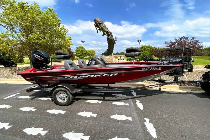 Slide: The Image of 2022 Tracker Pro Team 175 TXW boat on trailer, parked outdoors with trees and sculpture. - 8