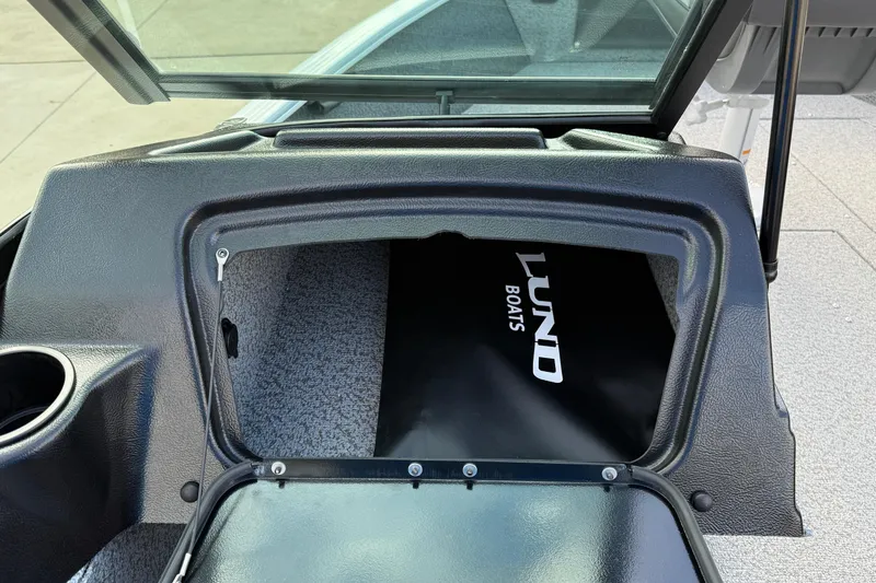 Slide: The Image of 2026 Lund 1675 Adventure Sport boat storage compartment with open hatch and visible logo. - 23