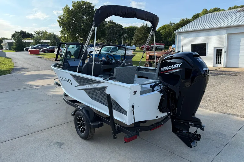 Slide: The Image of 2026 Lund 1675 Adventure Sport boat with Mercury engine on trailer, parked outdoors. - 5