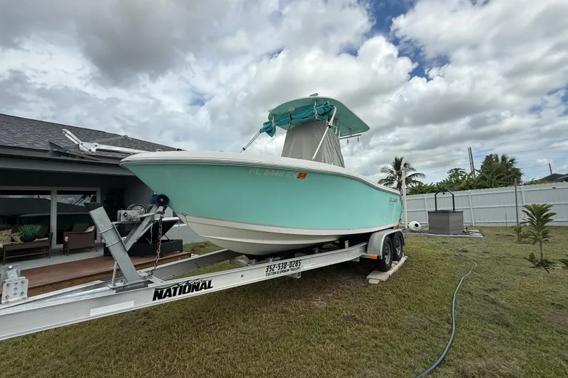 The Image of 2018 Release 208 RX boat on trailer, parked in a grassy yard under cloudy sky. - 1
