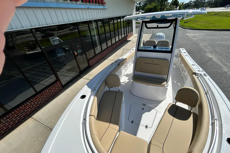 Slide: The Image of 2026 Sportsman Open 232 Center Console boat with tan seating, parked outside a building. - 21