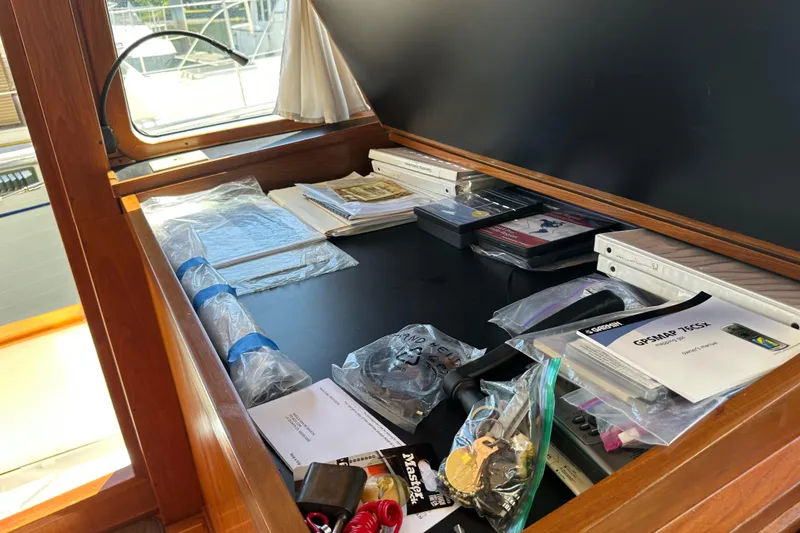 Slide: The Image of Navigation desk on 2000 Eagle 40 Pilothouse Trawler with maps, manuals, and equipment. - 33