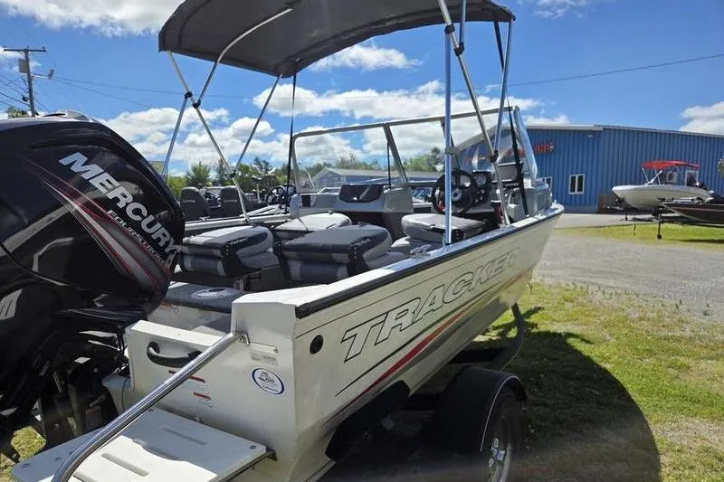 Slide: The Image of 2018 Tracker PG V16 WT boat with Mercury engine, parked outdoors under blue sky. - 3