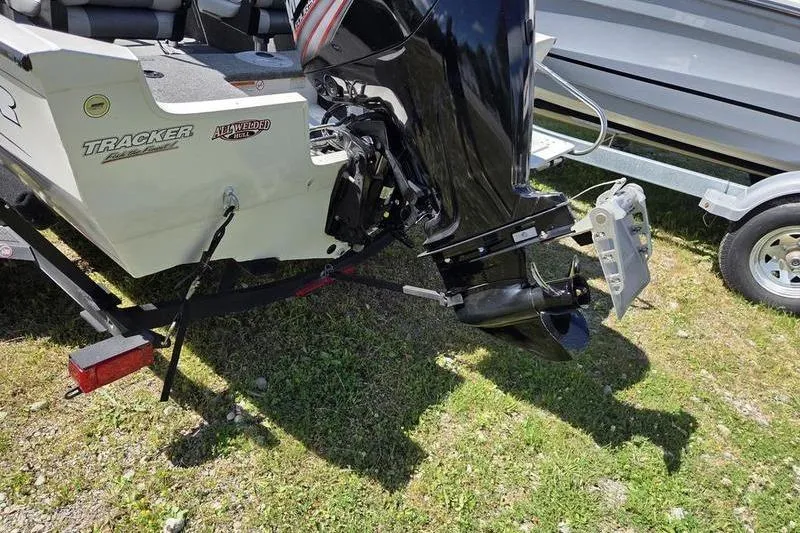 Slide: The Image of 2018 Tracker PG V16 WT boat with outboard motor on trailer, parked on grass. - 6
