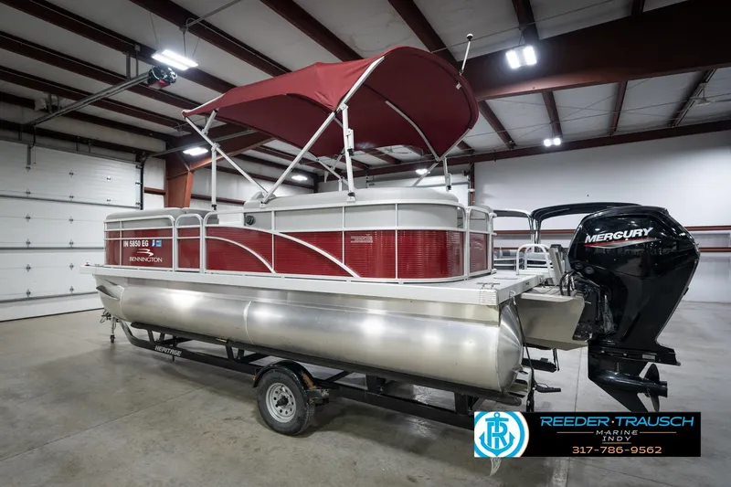 Slide: The Image of 2021 Bennington 20 SVSR pontoon boat with red canopy and Mercury outboard motor in a garage. - 10