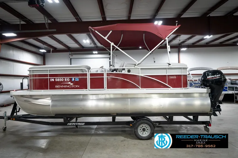 Slide: The Image of 2021 Bennington 20 SVSR pontoon boat with red canopy in indoor showroom. - 11