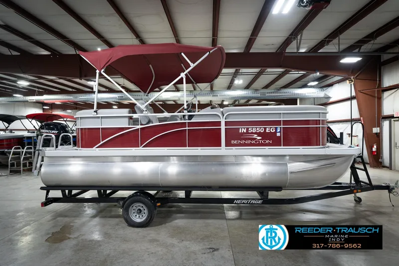 Slide: The Image of 2021 Bennington 20 SVSR pontoon boat with red canopy in indoor showroom. - 7