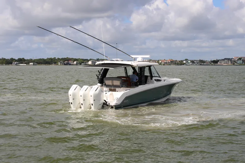 Slide: The Image of 2026 Boston Whaler 350 Realm on calm water with three outboard engines and fishing rods. - 3