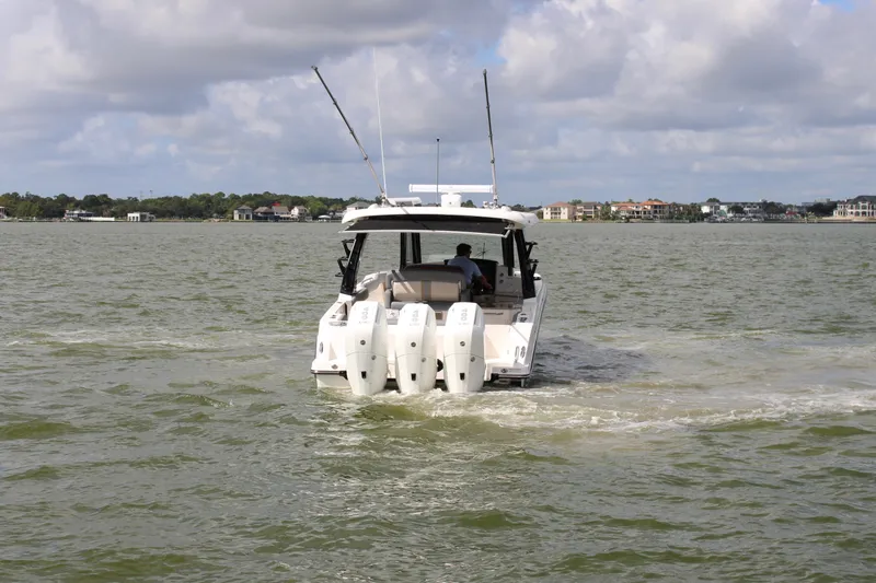 Slide: The Image of A 2026 Boston Whaler 350 Realm cruising on calm waters with four outboard engines. - 2