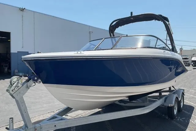 Slide: The Image of 2025 Bayliner V20i boat on trailer, blue and white design, parked outdoors. - 3