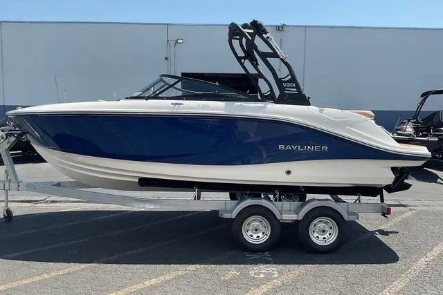 Slide: The Image of 2025 Bayliner V20i boat on trailer, blue and white design, parked outdoors. - 4