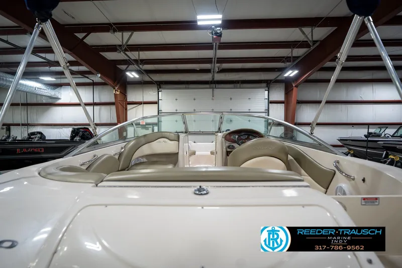 Slide: The Image of 2005 Sea Ray 200 Sundeck boat interior in showroom, featuring beige seating and sleek design. - 20