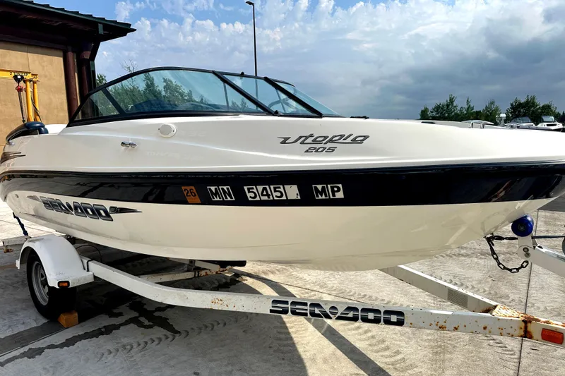 Slide: The Image of 2003 Sea-Doo Utopia 185 boat on trailer, parked outdoors under cloudy sky. - 2