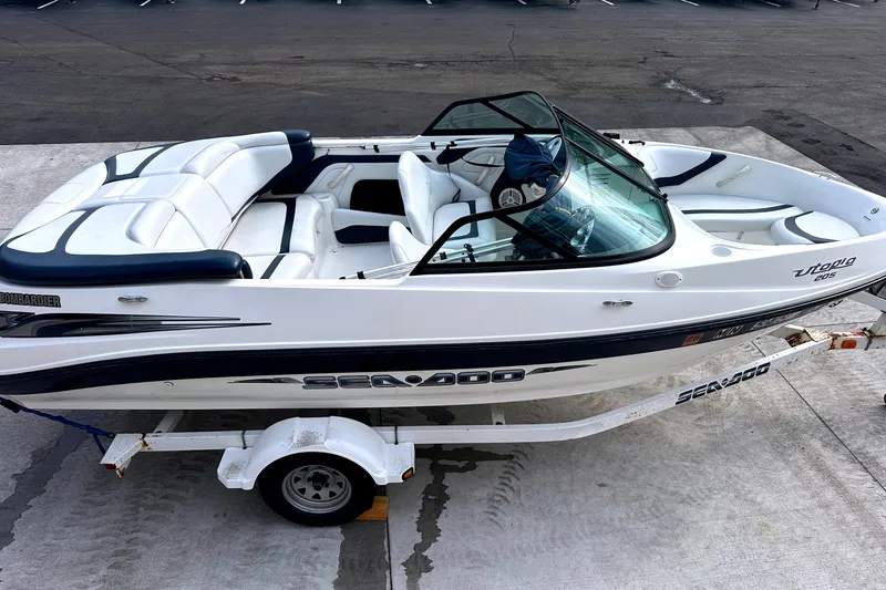 Slide: The Image of 2003 Sea-Doo Utopia 185 boat on trailer, white and blue design, parked on concrete. - 8