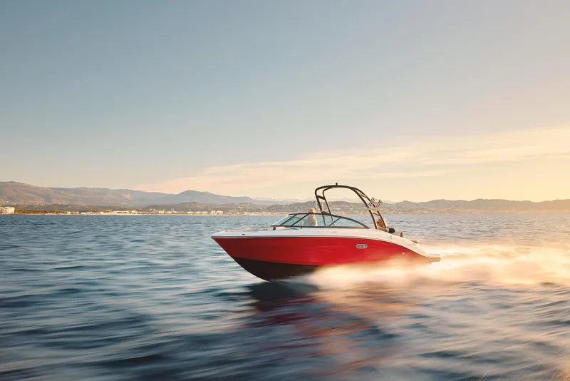 The Image of 2026 Sea Ray SPX 210 boat with red hull on trailer in showroom. - 1