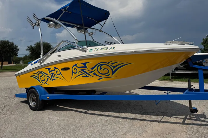 The Image of 2007 Sea Ray 195 Sport boat with vibrant yellow and blue graphics on a trailer. - 1