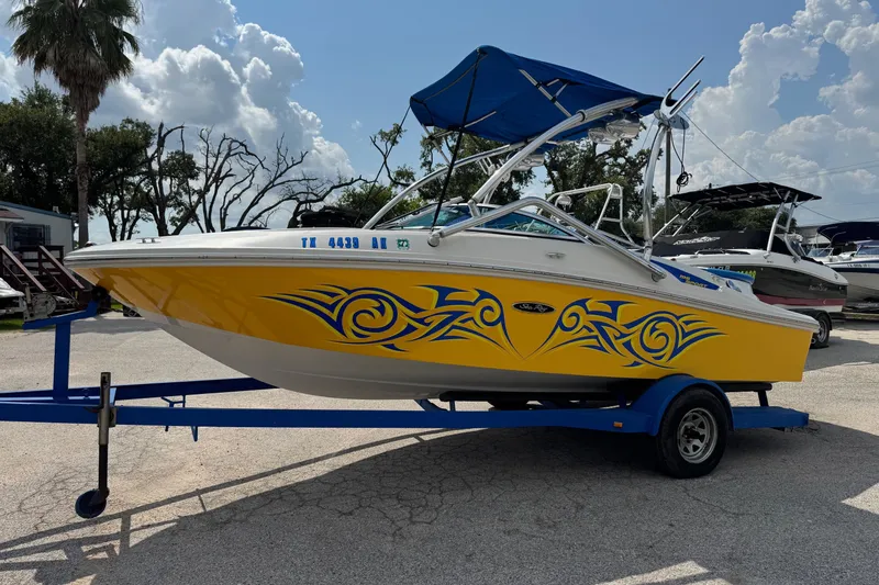 Slide: The Image of 2007 Sea Ray 195 Sport boat with vibrant yellow and blue tribal design on trailer. - 6