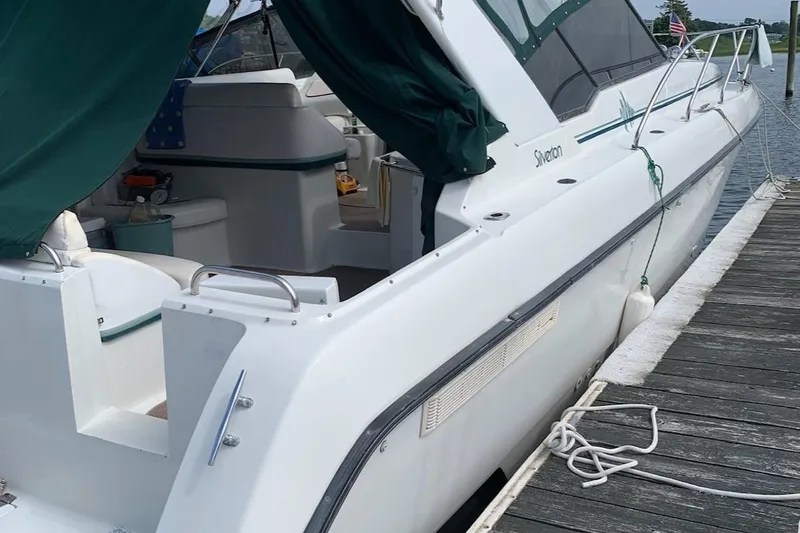 Slide: The Image of 1993 Silverton 34 Express yacht docked, featuring a white exterior and green canopy. - 2