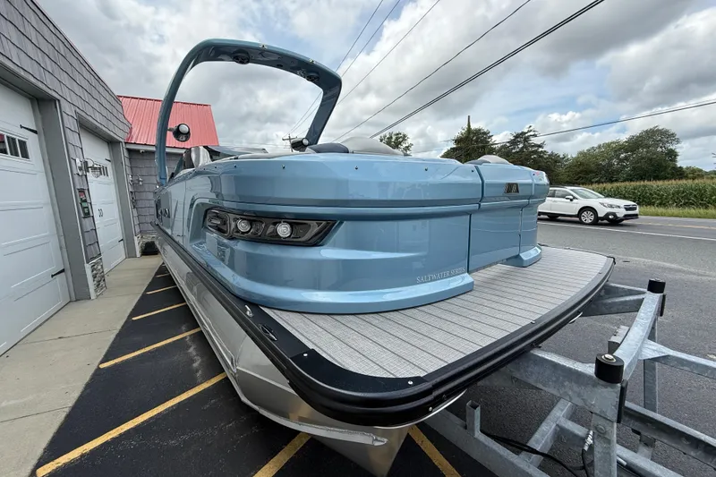 Slide: The Image of 2026 Avalon 2585 Excalibur Windshield Quad Lounger, blue tri-toon boat on trailer. - 10
