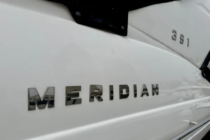 Slide: The Image of 2014 Meridian 391 Sedan boat nameplate with chrome lettering on white hull. - 5