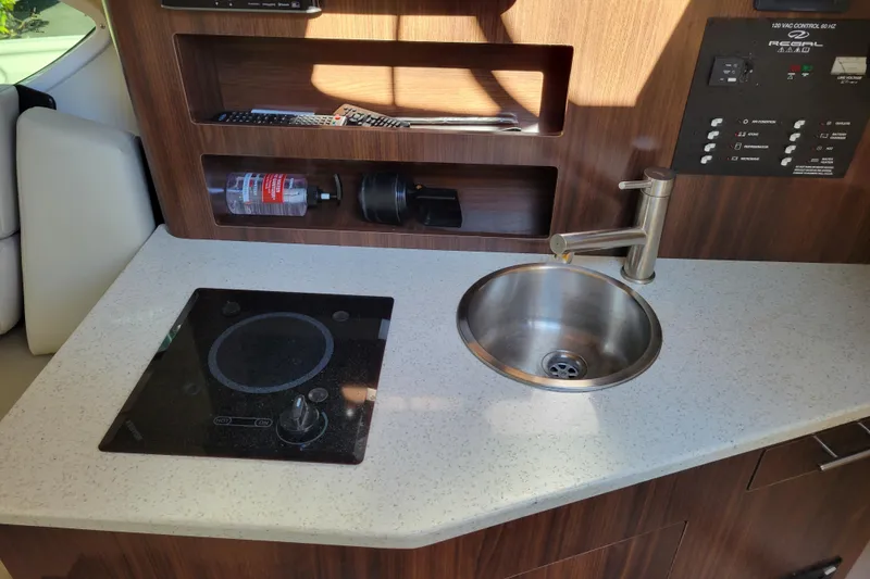 Slide: The Image of Microwave in 2018 Regal 26 Express boat interior, featuring wood paneling and control panel. - 26