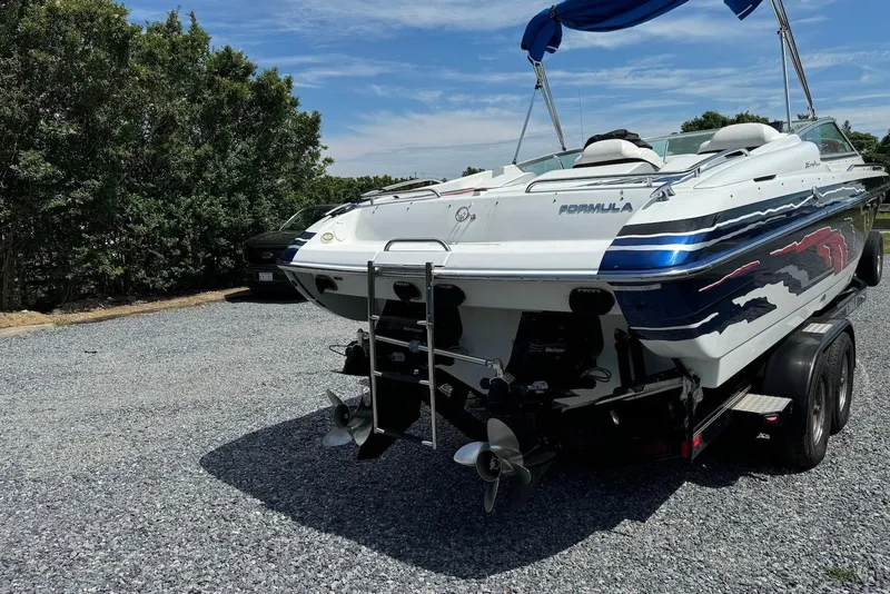 Slide: The Image of 2005 Formula 292 FASTech boat on trailer, parked on gravel, with trees in background. - 2