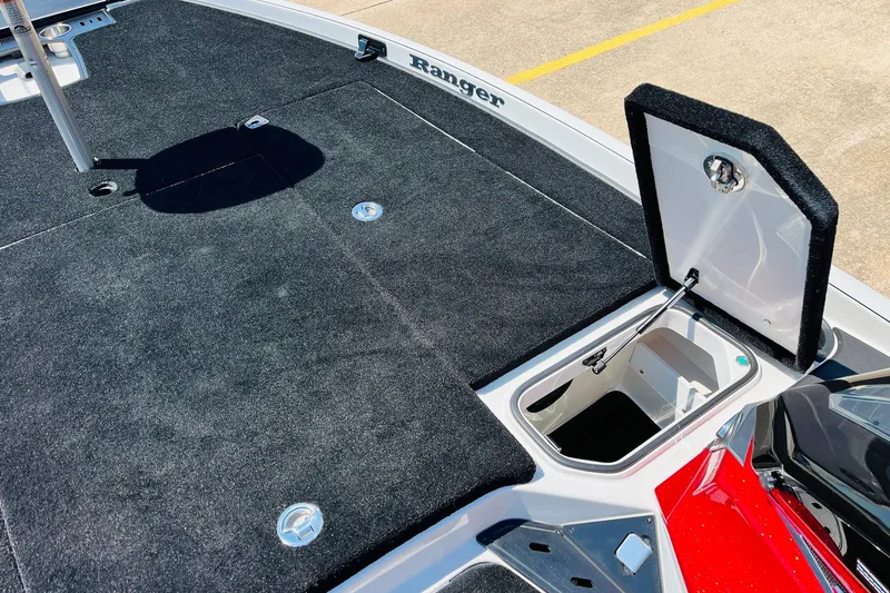 Slide: The Image of 2025 Ranger Z520 boat deck with open storage compartment, black carpet, and red accents. - 20