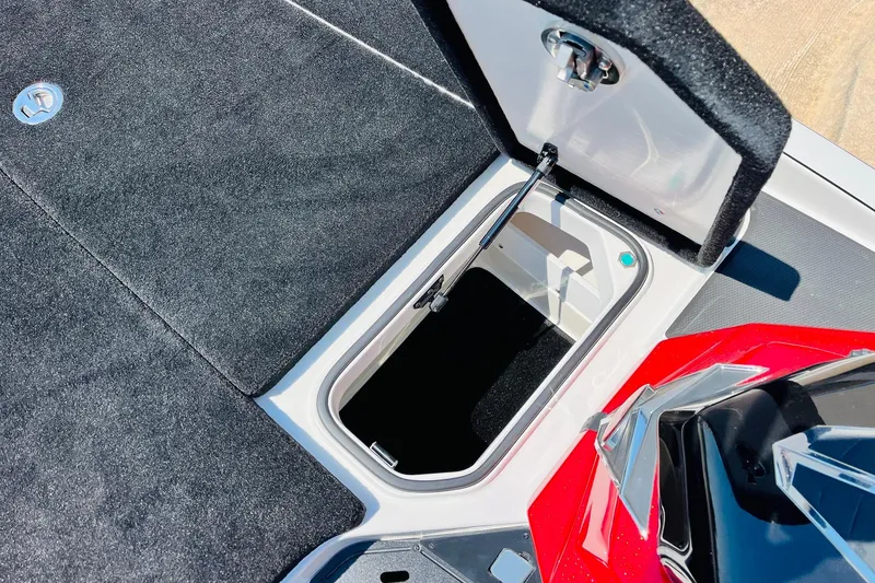 Slide: The Image of Open storage compartment on 2025 Ranger Z520 boat, featuring carpeted interior and hydraulic lift. - 21