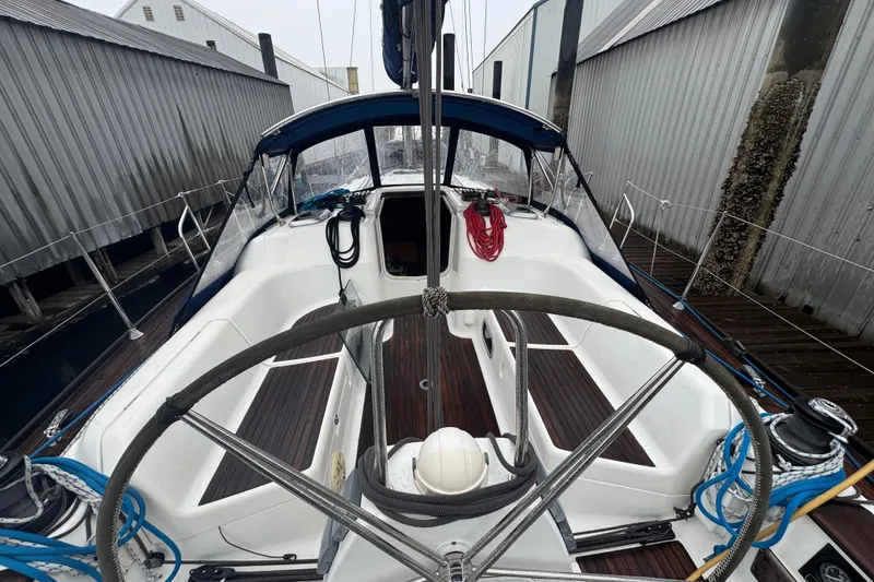 Slide: The Image of 2004 Dufour 40 Performance sailboat cockpit with steering wheel, docked between buildings. - 5
