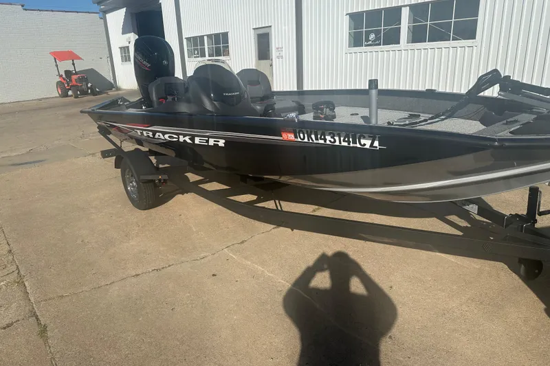 Slide: The Image of 2024 Tracker Pro Team 175 TF boat on trailer, parked outside a building. - 2