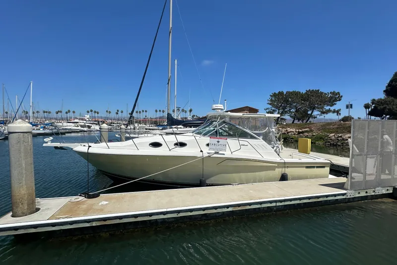 The Image of 2003 Wellcraft 330 Coastal boat docked at marina under clear blue sky. - 0