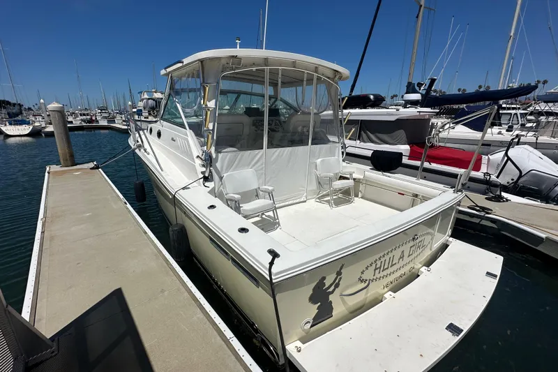 Slide: The Image of 2003 Wellcraft 330 Coastal boat docked at marina, featuring spacious deck and clear skies. - 4