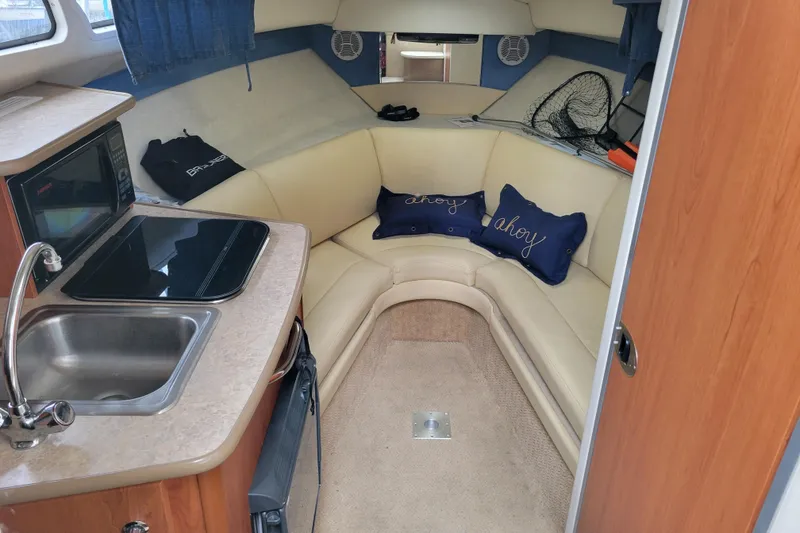 Slide: The Image of 2007 Bayliner 245 Cruiser interior with kitchenette, sink, and cozy seating area. - 18