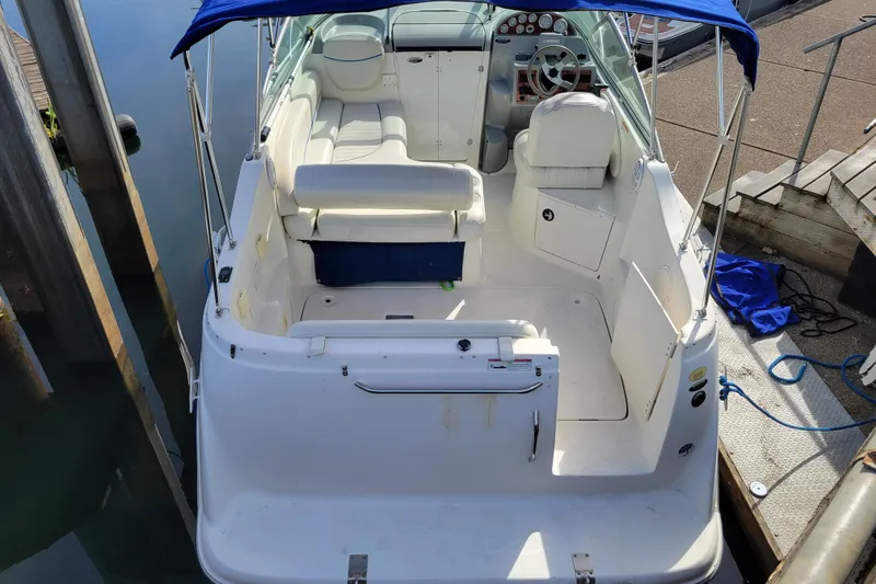 Slide: The Image of 2007 Bayliner 245 Cruiser boat with white interior and blue canopy at dock. - 2