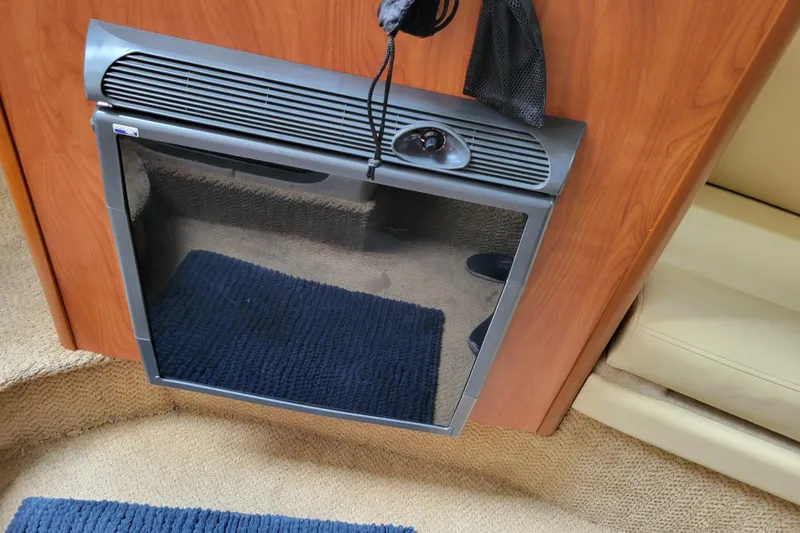 Slide: The Image of 2007 Bayliner 245 Cruiser interior with compact fridge and wooden cabinetry. - 21