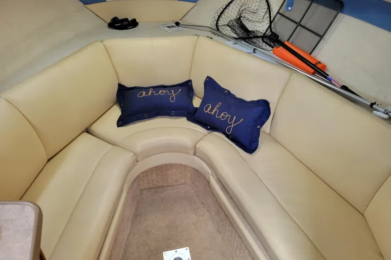 Slide: The Image of 2007 Bayliner 245 Cruiser interior with beige seating, "ahoy" pillows, and fishing gear. - 24