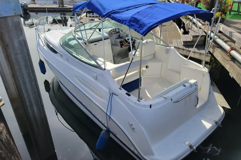 Slide: The Image of 2007 Bayliner 245 Cruiser with blue canopy docked at marina. - 3