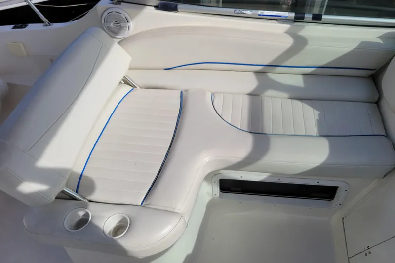 Slide: The Image of 2007 Bayliner 245 Cruiser interior seating with white upholstery and cup holders. - 7