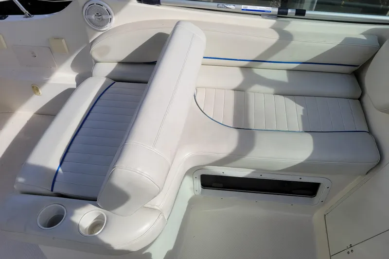 Slide: The Image of 2007 Bayliner 245 Cruiser interior seating with white upholstery and cup holders. - 8