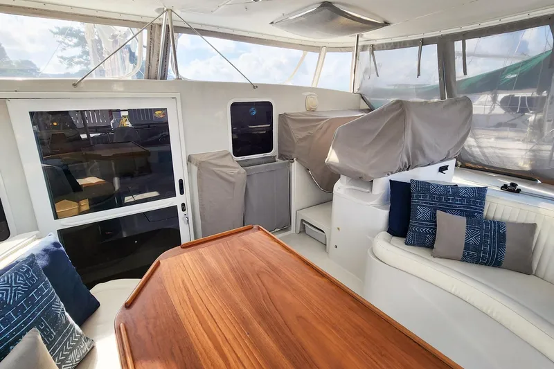 Slide: The Image of 2007 Antares Catamarans PDQ 44i interior with wooden table, cushioned seating, and covered equipment. - 21
