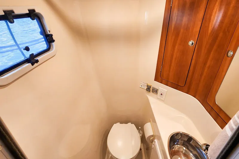 Slide: The Image of 2007 Antares Catamarans PDQ 44i bathroom with porthole, wooden cabinets, and compact toilet. - 42