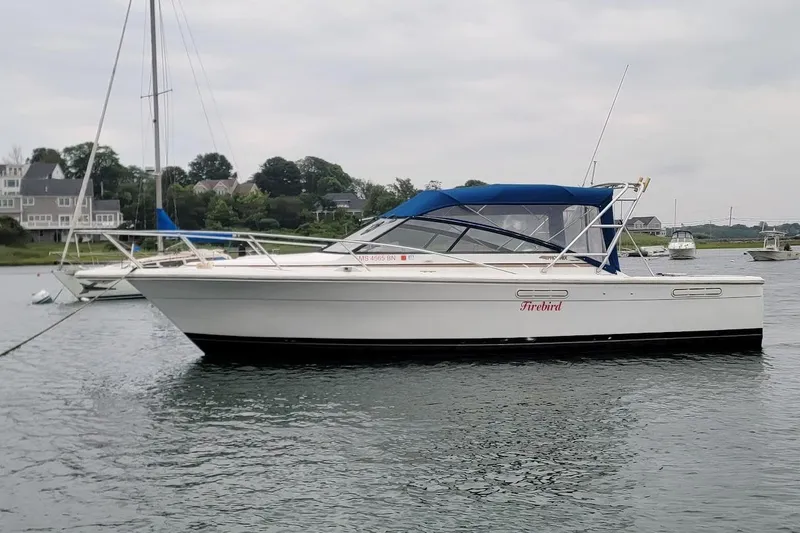 Slide: The Image of 1996 Phoenix 34 Tournament boat with blue canopy, docked in a scenic harbor. - 23